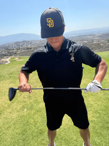 Model in 6th Panel Golf Polo holding a golf club on a golf course