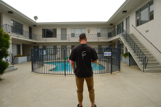 Men’s black oversized tee in large size standing in front of a pool.